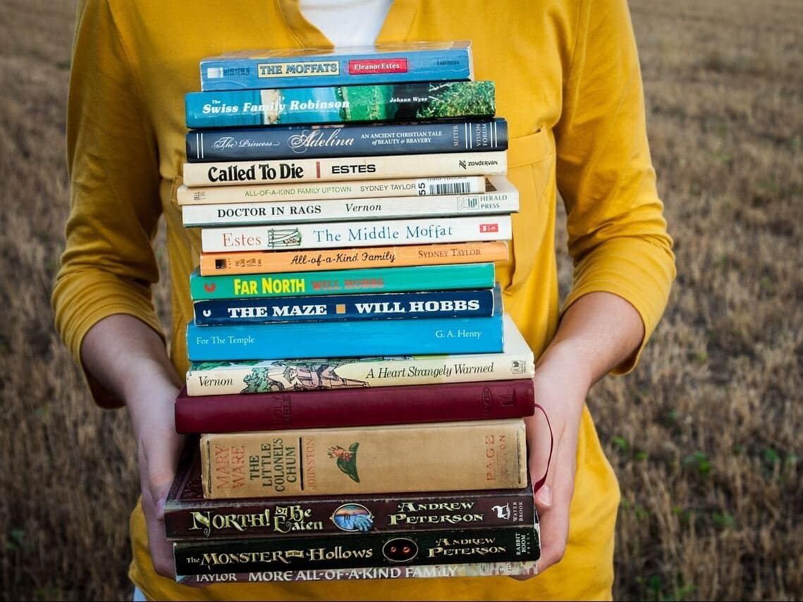 Frau mit einem Stapel Bücher in einem Feld