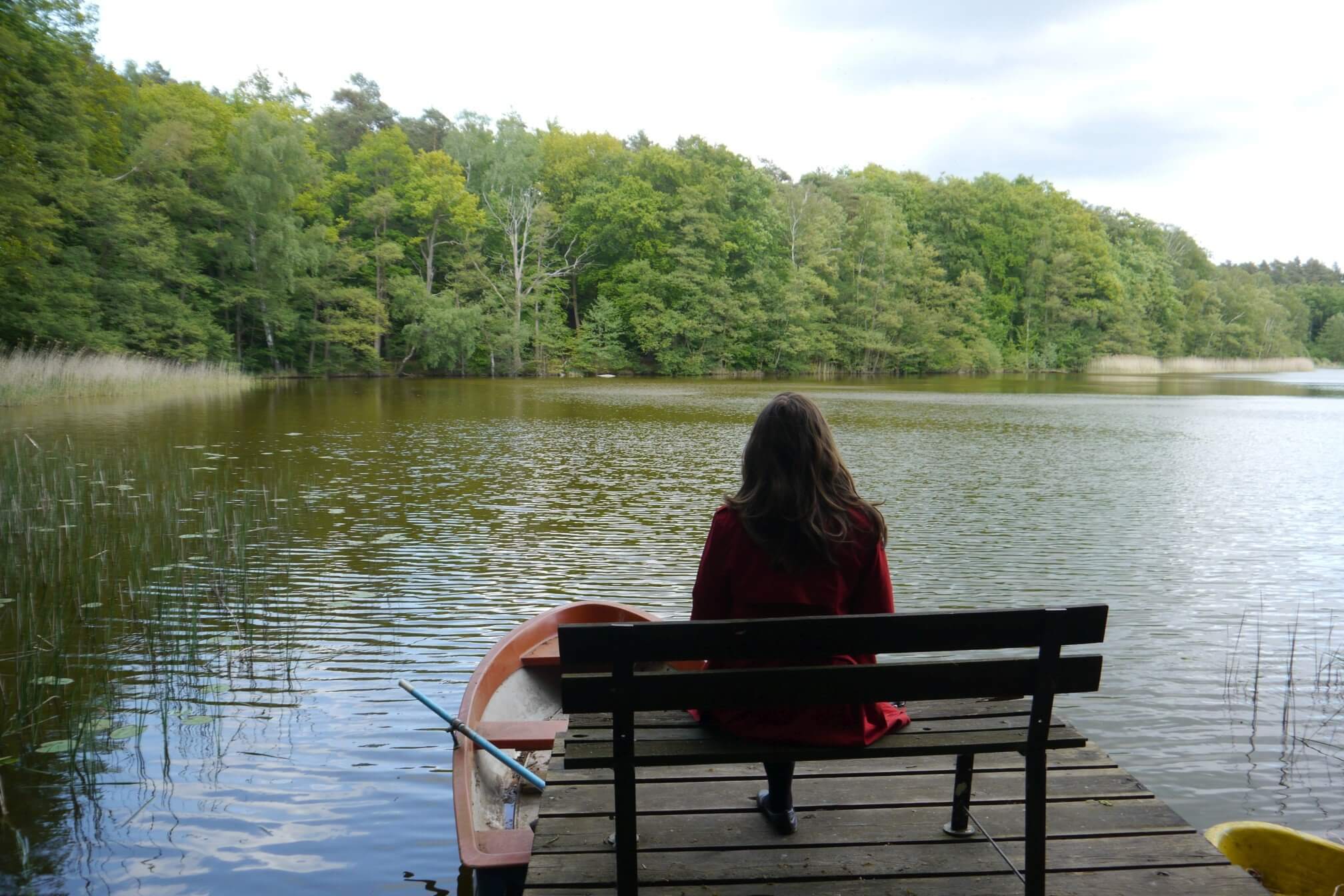 Eine Frau sitzt auf einer Bank am See